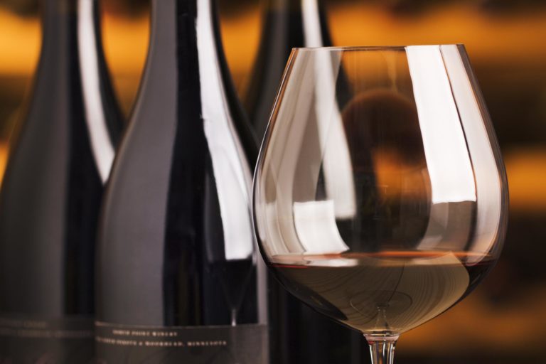 Weinflaschen und ein Glas Rotwein